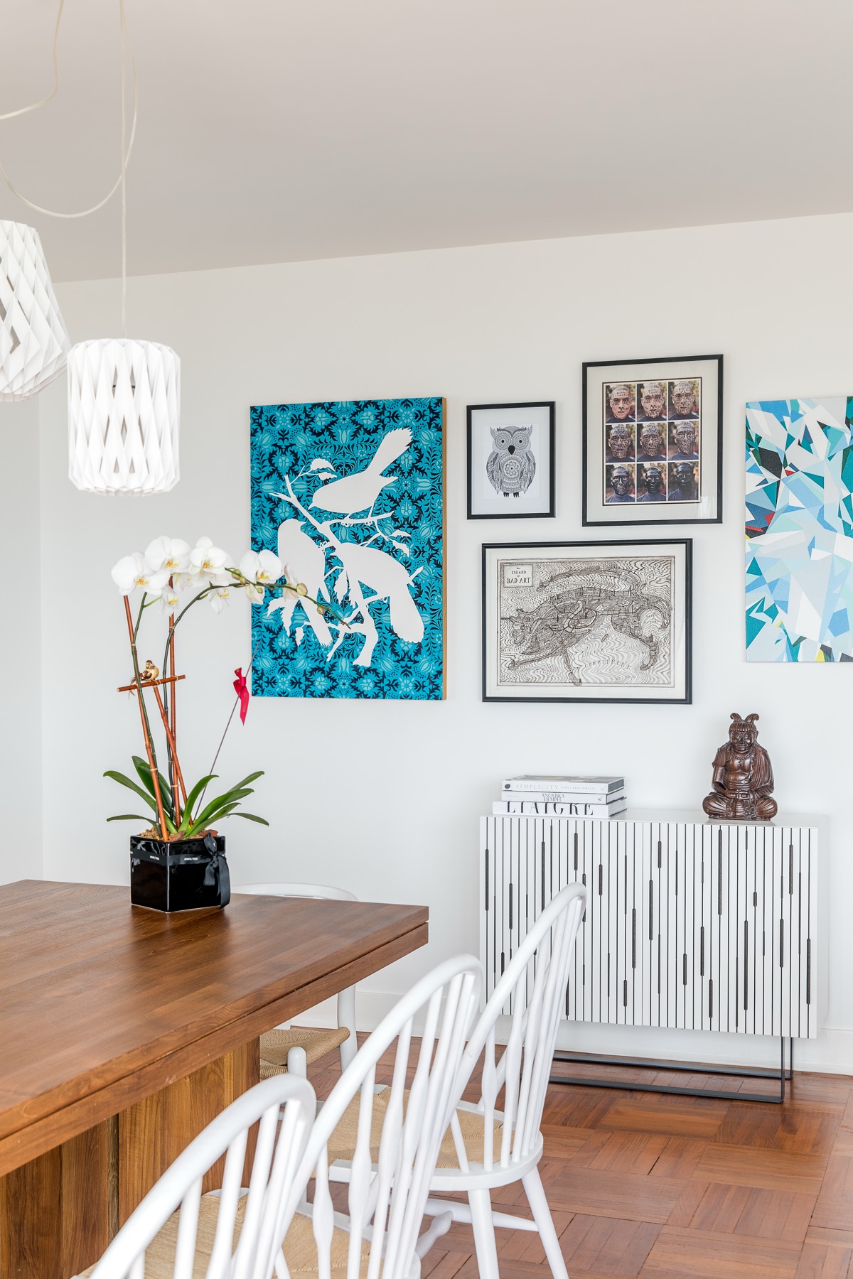 Gallery wall above a timber dining table with white chairs in Pattern Play