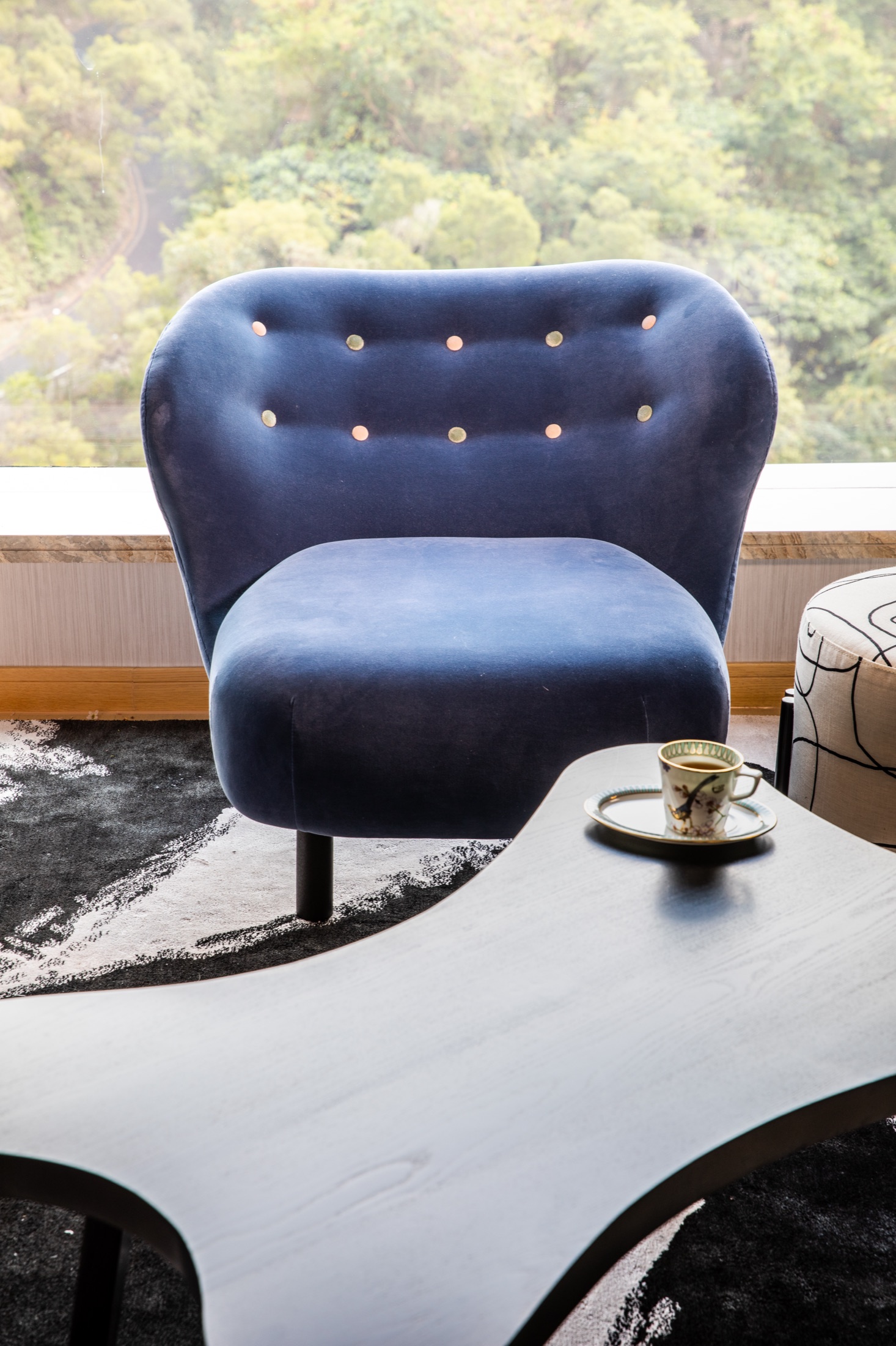 Blue sculpted armchair beside a window and curved coffee table